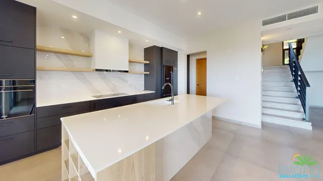Kitchen with a large island and staircase at Plumbago Residences
